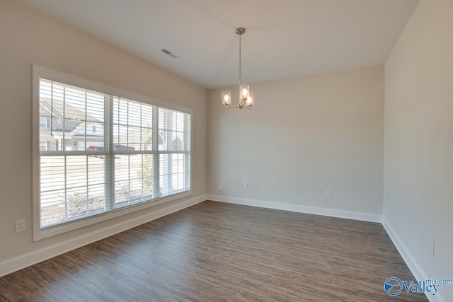 unfurnished room with dark wood-type flooring, a chandelier, and a healthy amount of sunlight