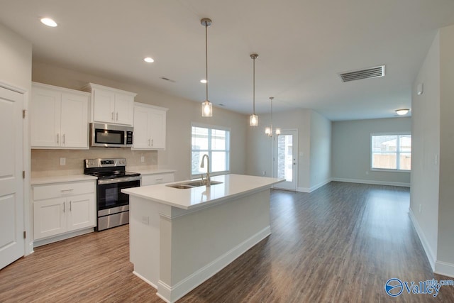 kitchen with sink, white cabinetry, appliances with stainless steel finishes, and an island with sink