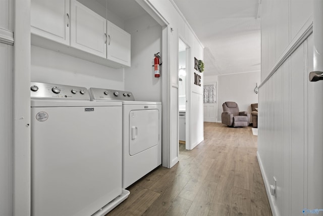 laundry room with separate washer and dryer, cabinets, and wood-type flooring