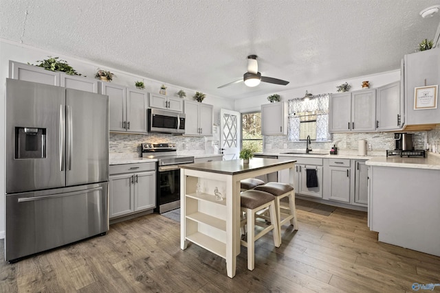 kitchen featuring stainless steel appliances, ceiling fan, sink, hardwood / wood-style flooring, and a center island