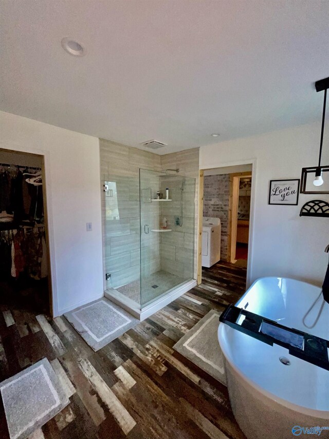 bathroom featuring hardwood / wood-style floors, washer / dryer, and an enclosed shower