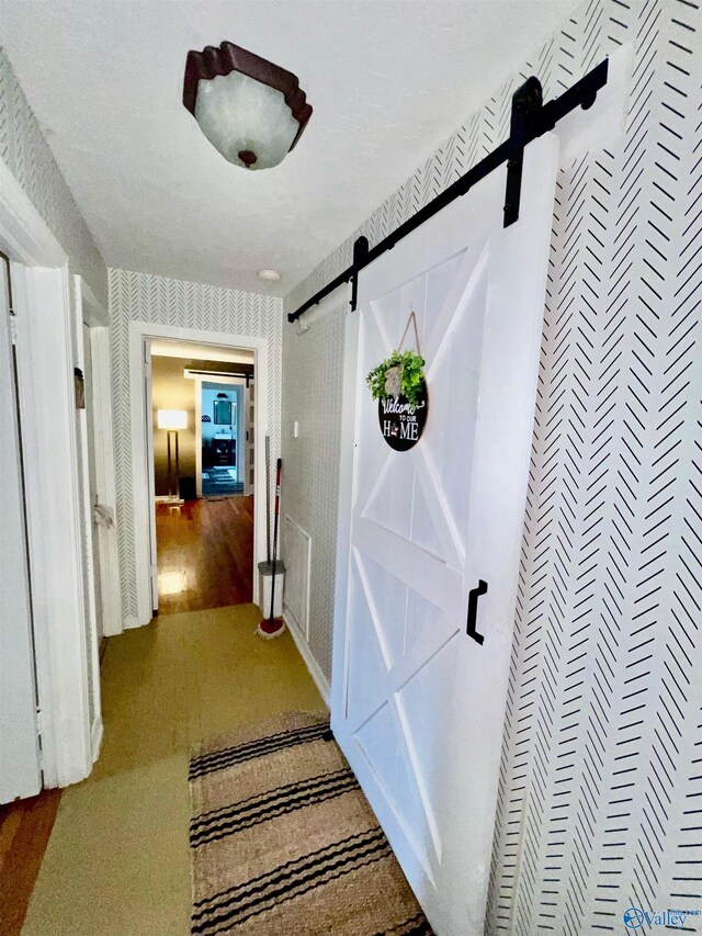 hallway with a barn door and hardwood / wood-style floors