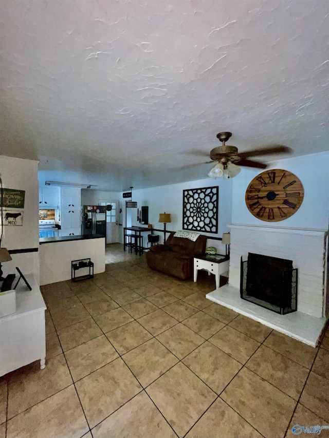 living room with a textured ceiling, light tile patterned floors, and ceiling fan