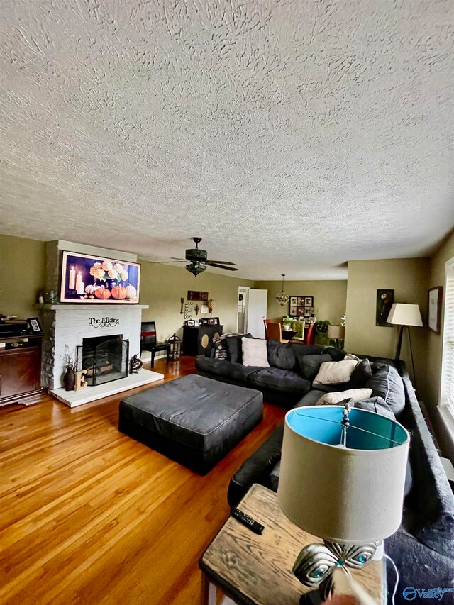 living room with a textured ceiling, hardwood / wood-style flooring, and ceiling fan