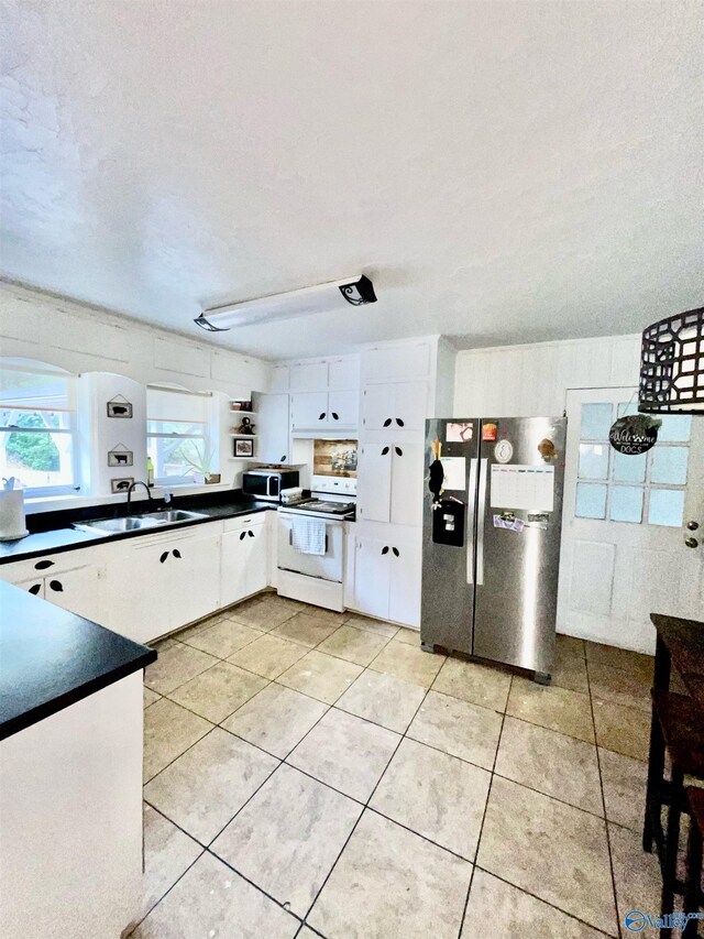 kitchen featuring white range with electric cooktop, white cabinets, stainless steel refrigerator with ice dispenser, a textured ceiling, and sink