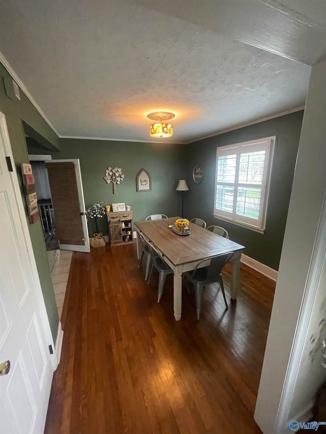 dining space featuring dark hardwood / wood-style flooring, ornamental molding, and a textured ceiling