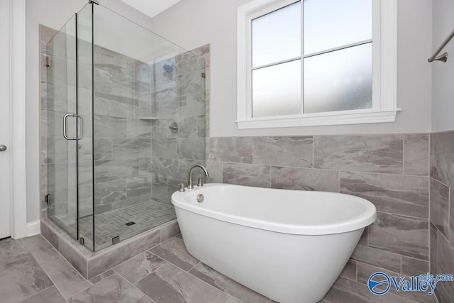 bathroom featuring tile walls and independent shower and bath