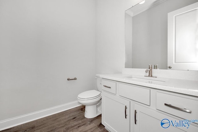 bathroom with wood-type flooring, vanity, and toilet