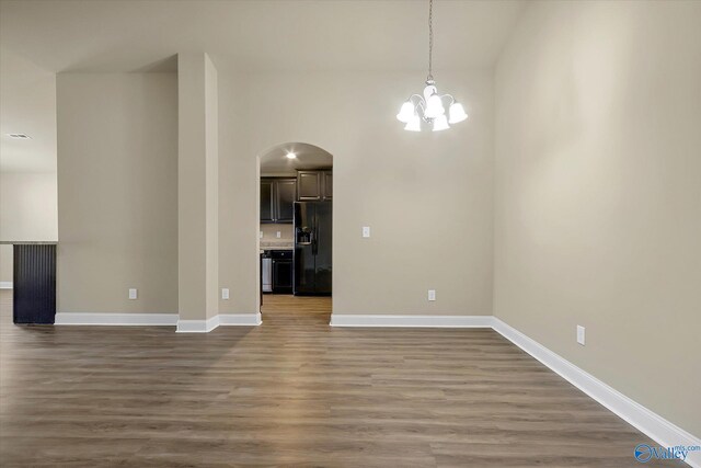 kitchen featuring pendant lighting, lofted ceiling, black fridge with ice dispenser, and light hardwood / wood-style flooring