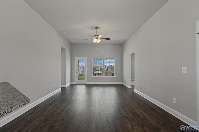 empty room with dark wood-style flooring, ceiling fan, and baseboards