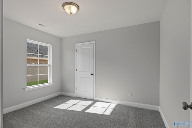 carpeted spare room featuring visible vents and baseboards