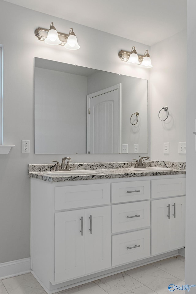 full bathroom featuring marble finish floor, double vanity, and a sink