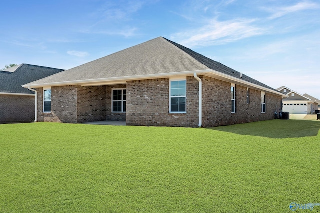 back of property featuring a yard, brick siding, roof with shingles, and a patio area