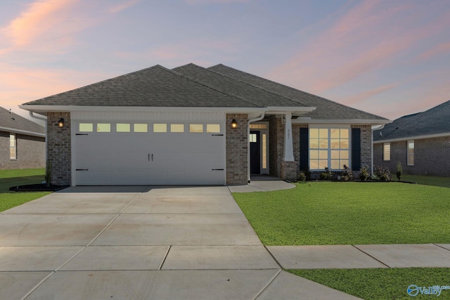 prairie-style home featuring a garage, driveway, a front lawn, and a shingled roof