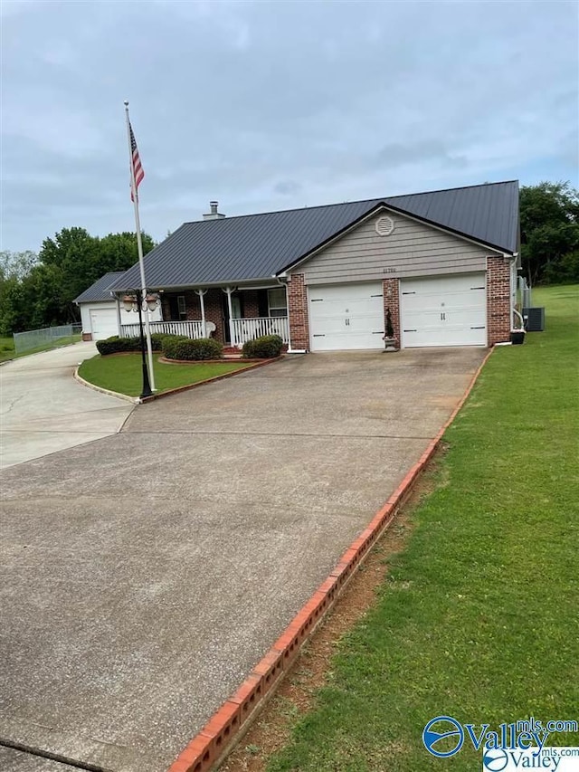 view of front facade with concrete driveway, a front yard, brick siding, and metal roof