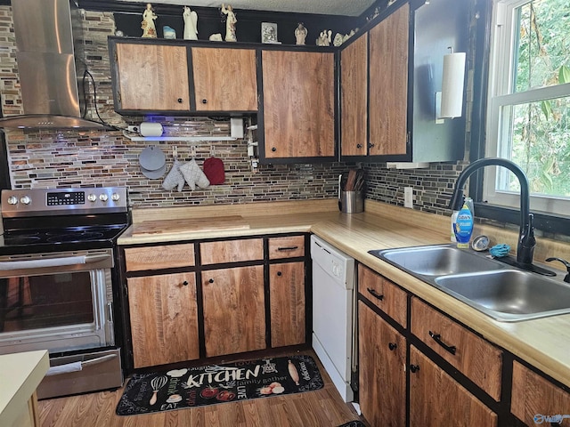 kitchen with stainless steel electric range, dishwasher, sink, wall chimney exhaust hood, and light hardwood / wood-style flooring