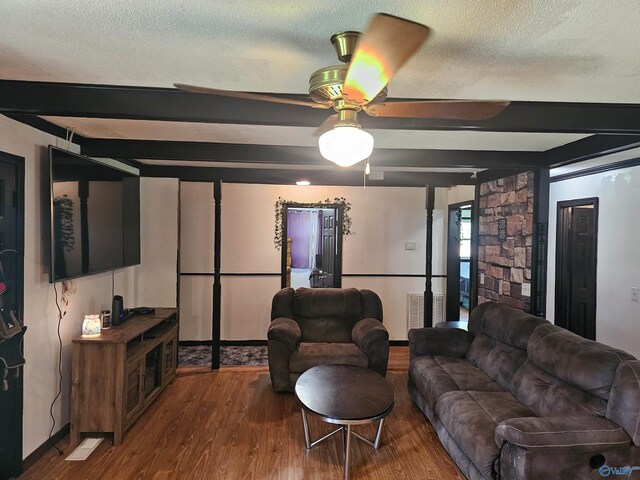 living room with beamed ceiling, wood-type flooring, ceiling fan, and a textured ceiling