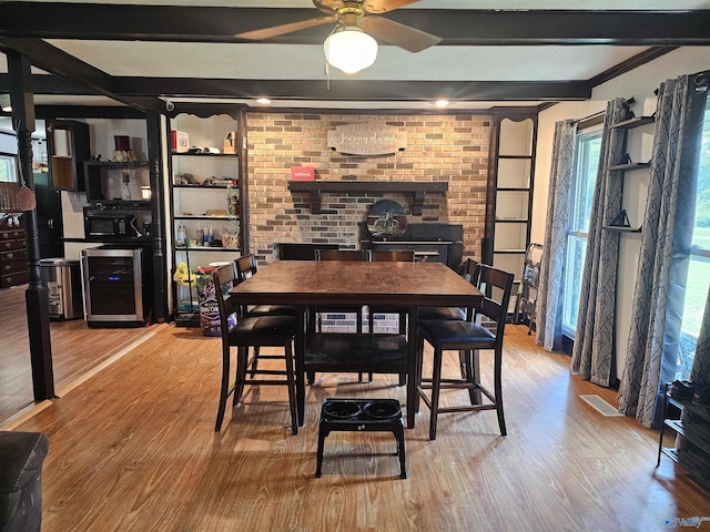 dining space with beam ceiling, wood-type flooring, beverage cooler, and brick wall