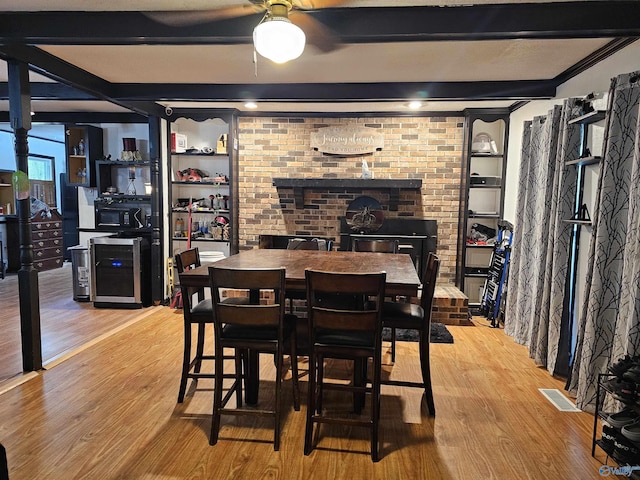 dining area with wood-type flooring, brick wall, and beam ceiling