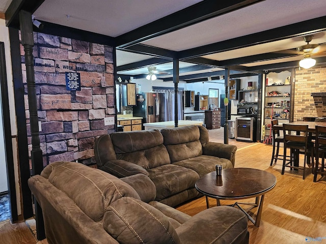 living room with beamed ceiling, ceiling fan, and light wood-type flooring