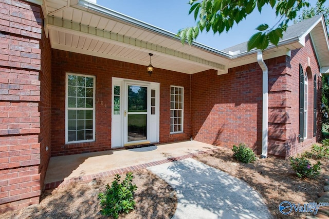 entrance to property featuring a patio and brick siding