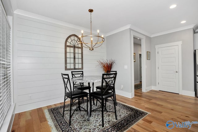 dining space featuring a chandelier, hardwood / wood-style floors, crown molding, and wood walls