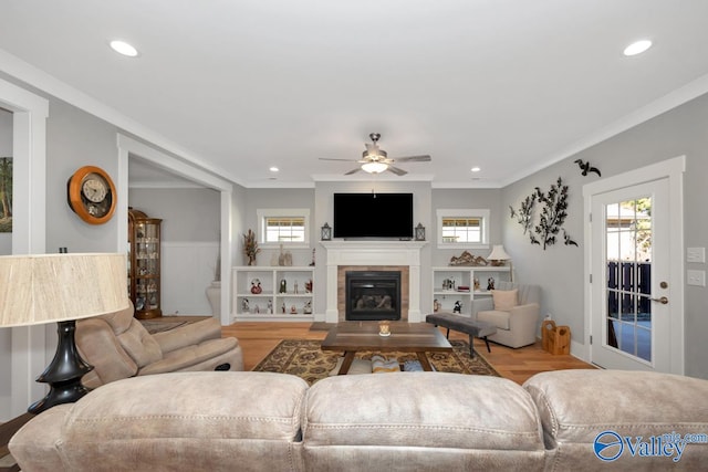 living room featuring light wood-type flooring, ceiling fan, and ornamental molding