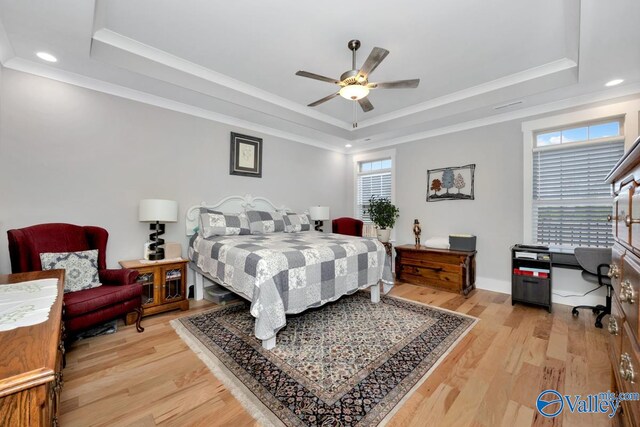 bedroom featuring ceiling fan, light wood-type flooring, crown molding, and a tray ceiling