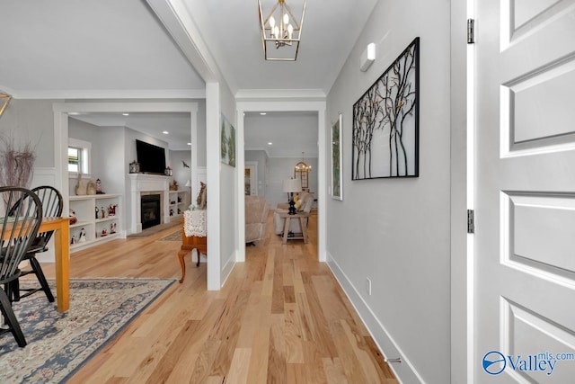 foyer with a chandelier, light hardwood / wood-style flooring, and crown molding