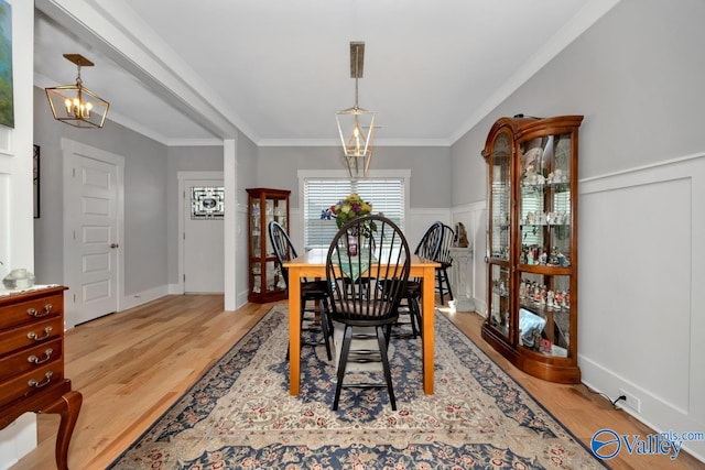 dining room with light hardwood / wood-style floors, crown molding, and an inviting chandelier