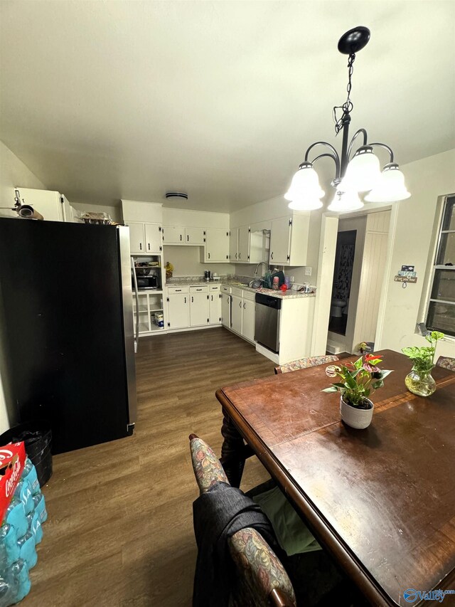 dining area with sink, dark wood-type flooring, and a chandelier