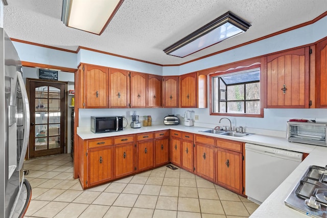 kitchen with brown cabinets, stainless steel appliances, light countertops, and a sink
