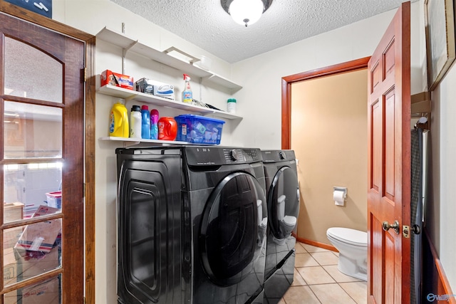 washroom with light tile patterned floors, baseboards, laundry area, separate washer and dryer, and a textured ceiling