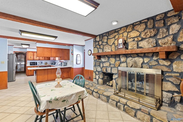 dining area featuring light tile patterned floors, a wainscoted wall, and a textured ceiling