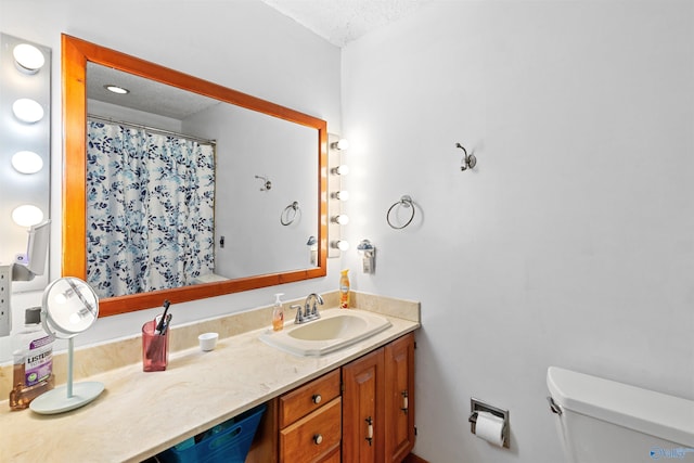 bathroom featuring curtained shower, toilet, vanity, and a textured ceiling
