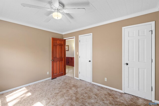 unfurnished bedroom featuring crown molding, baseboards, carpet floors, and ceiling fan
