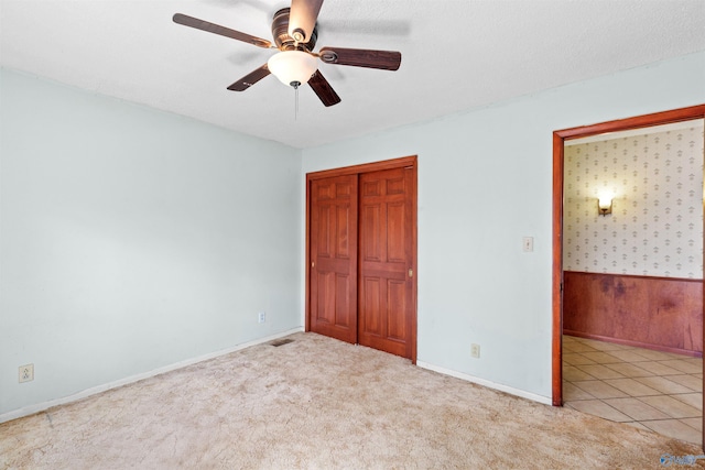 unfurnished bedroom with a closet, carpet, visible vents, and a ceiling fan