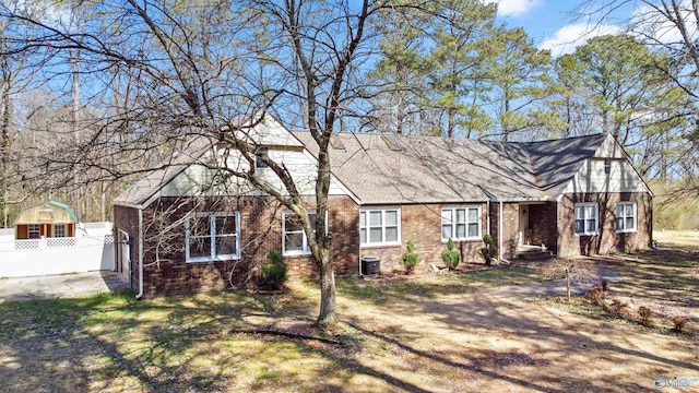 view of front of house featuring central air condition unit, brick siding, and fence