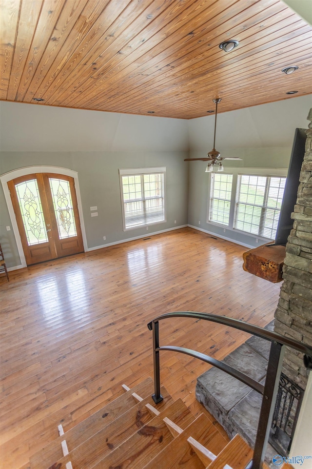 unfurnished living room with a wealth of natural light, light hardwood / wood-style floors, french doors, and wooden ceiling