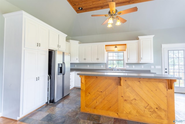 kitchen featuring a kitchen bar, sink, white cabinetry, stainless steel fridge with ice dispenser, and a kitchen island