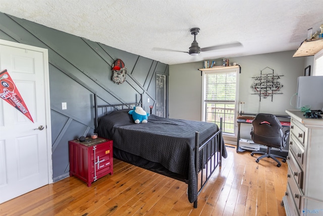 bedroom with ceiling fan, light hardwood / wood-style floors, and a textured ceiling