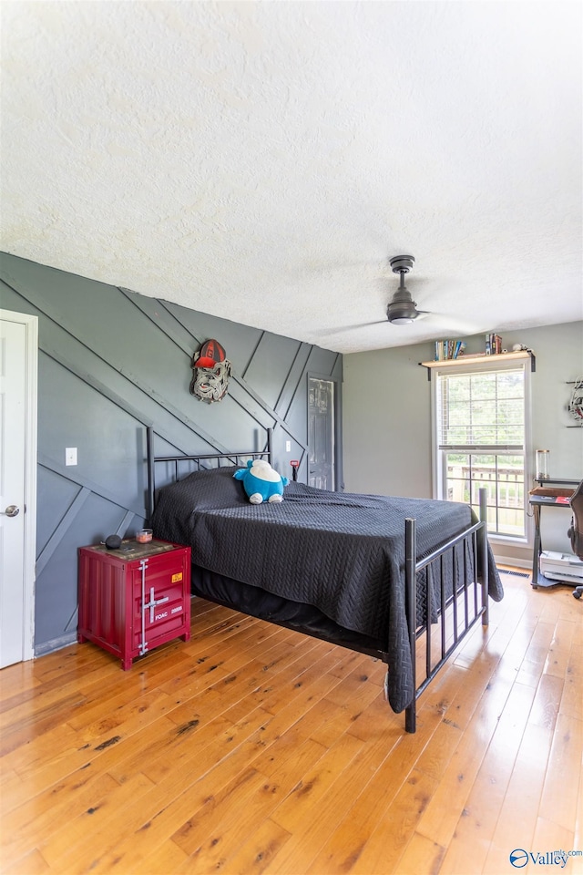 bedroom with hardwood / wood-style flooring, ceiling fan, and a textured ceiling