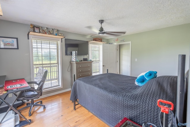 bedroom with ceiling fan, access to outside, hardwood / wood-style floors, and a textured ceiling