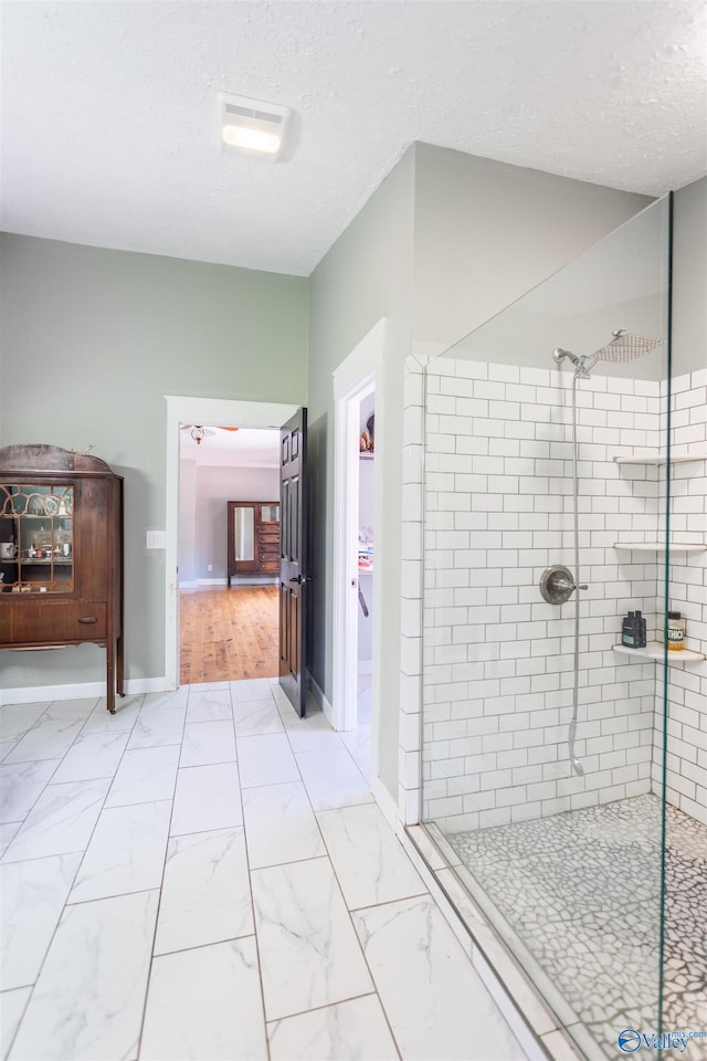 bathroom featuring tiled shower and a textured ceiling