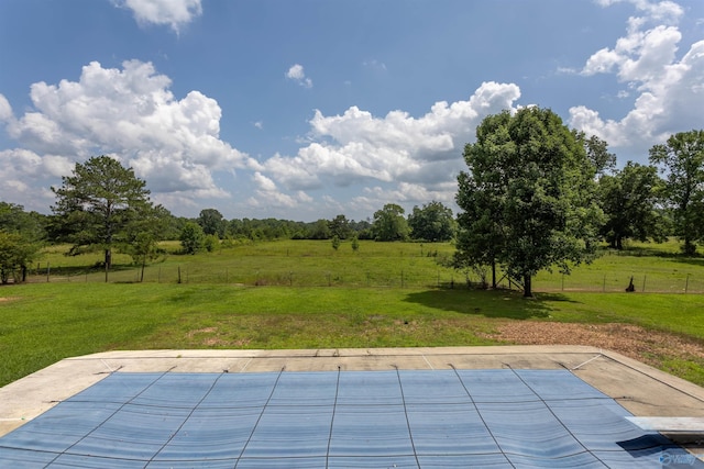 view of pool featuring a patio, a lawn, and a rural view