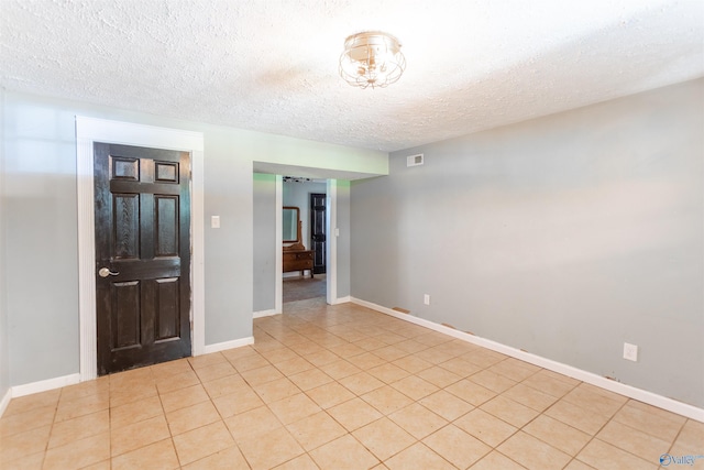 tiled empty room featuring a textured ceiling