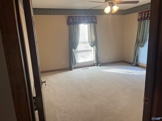 unfurnished room with ceiling fan, carpet floors, and a textured ceiling