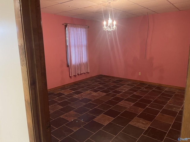 empty room with a paneled ceiling and a chandelier