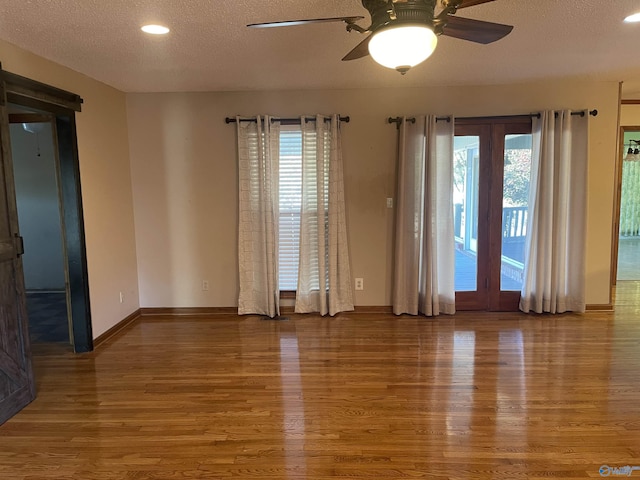 unfurnished room featuring hardwood / wood-style floors, ceiling fan, a healthy amount of sunlight, and a textured ceiling