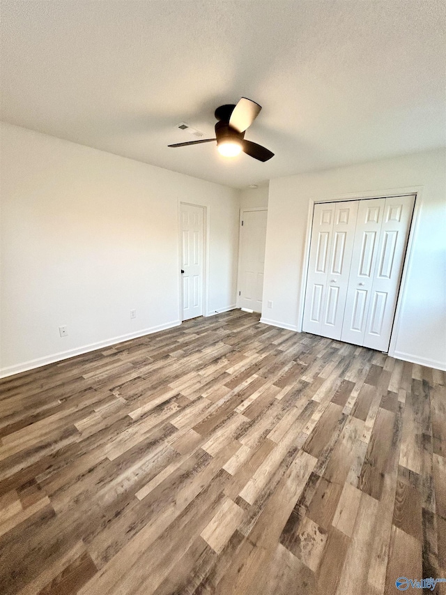 unfurnished bedroom with ceiling fan, hardwood / wood-style floors, a closet, and a textured ceiling